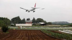 A plane landing over farmed fields