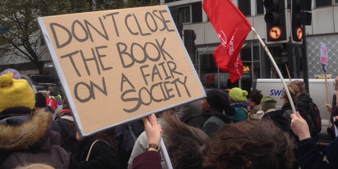 A plackard in a protest that reads "Don't close the book on a fair society"