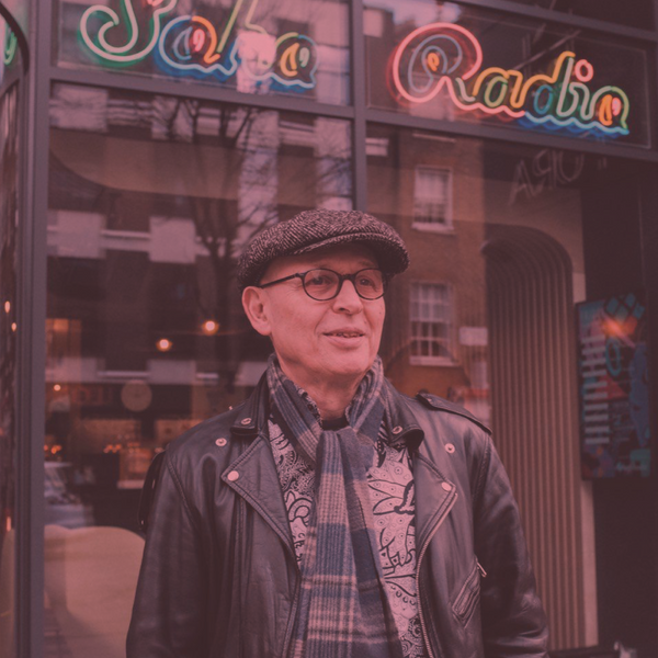A man stood infront of a shop window with a sign that reads "Soho Radio"