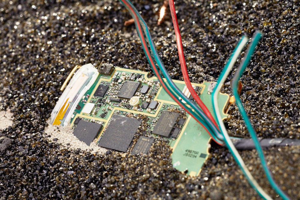 An electronic chip board half submerged in earth