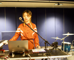 Profile image of Chen at a desk with computer, sound kit and microphone