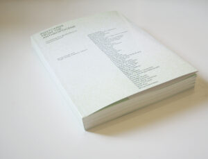 A book on a table, 'Postcards from the Anthropocene' a pale green cover with a list of names