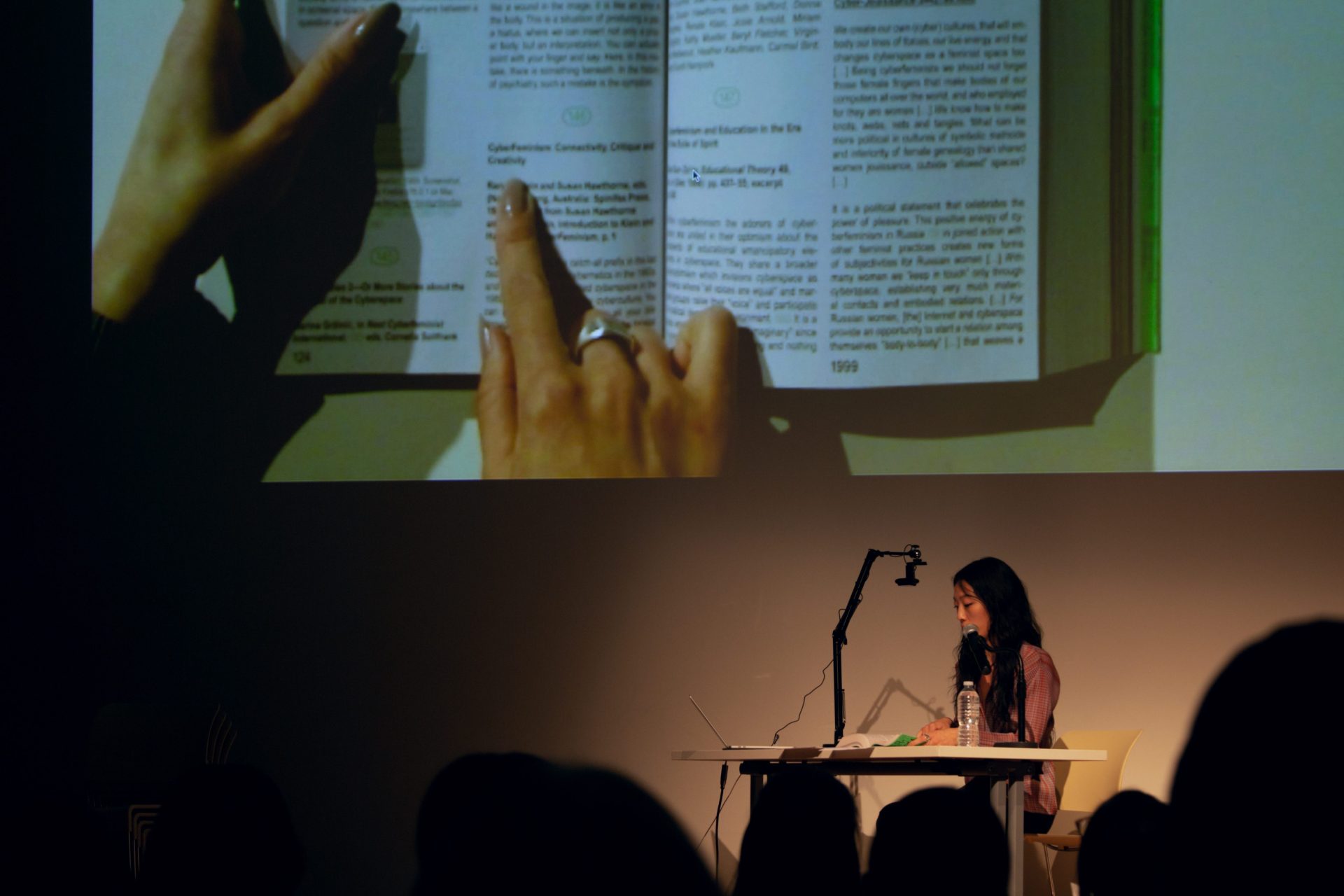 Mindy reading from a book that is being projected on a big screen