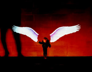 Album cover, a red image with a figure and two collaged white wings