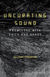 Book cover title 'Uncurating sound, knowledge with voice and hands' by author Salomé Voegelin. The background image is a black and white wood cut of a sea and landscape