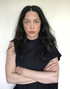 Luz María Sánchez looking at camera with folded arms in front of white background