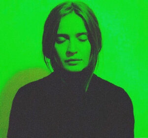 Sasha Kastoun stands with eyes closed with green colour tint and background