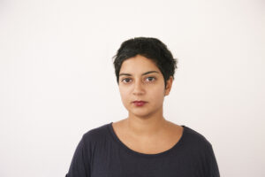 Syma Tariq stands in front of white wall