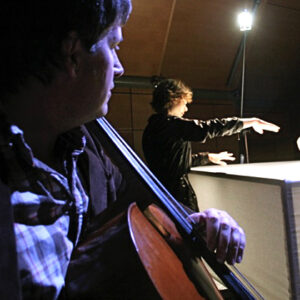 Thomas Gardner playing cello looking away from camera