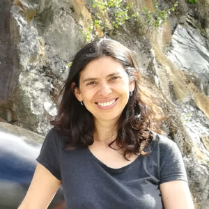 Ximena Alarcón-Díaz looks into the camera, standing in front of a rockface