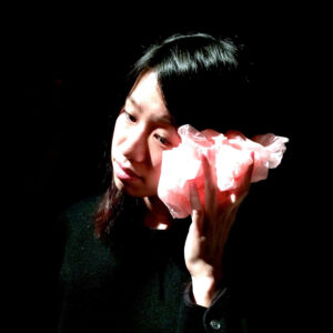 Tomoko Hojo holds scrunched fabric to her ear