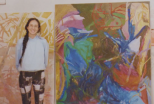 Ellie Wang smiling next to a painting